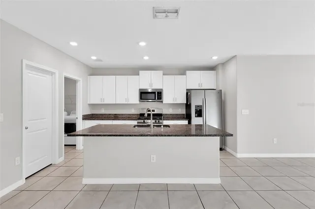 a large kitchen with granite countertop a large counter top and stainless steel appliances