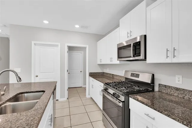 a kitchen with granite countertop a sink stove and microwave