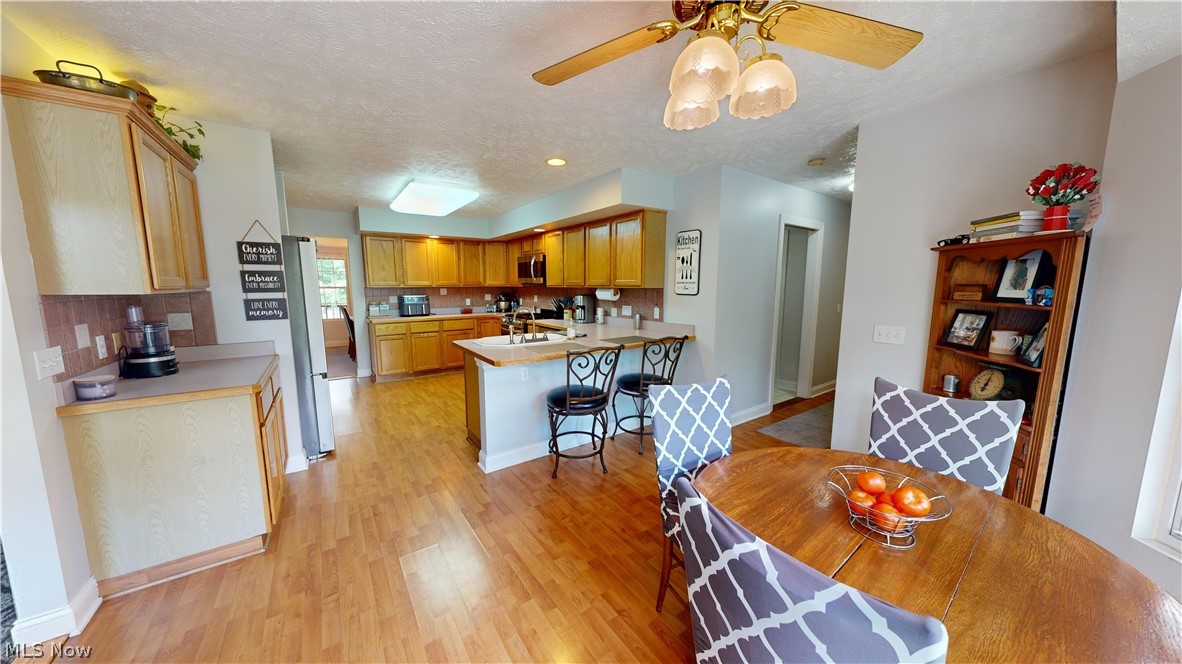 7115 Brakeman Road Painesville, OH 44077 - Photo 17 of 47 Dining area with sink, a textured ceiling, ceiling fan, and light hardwood / wood-style floors