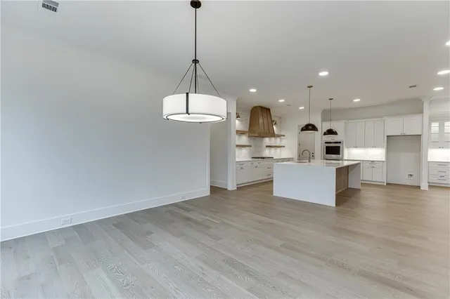 a view of an empty room with wooden floor and a chandelier