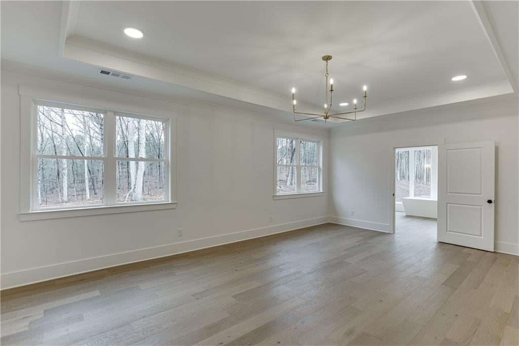 100 Gleneagles Way Pendergrass, GA 30567 - Photo 44 of 58 an empty room with wooden floor chandelier and windows