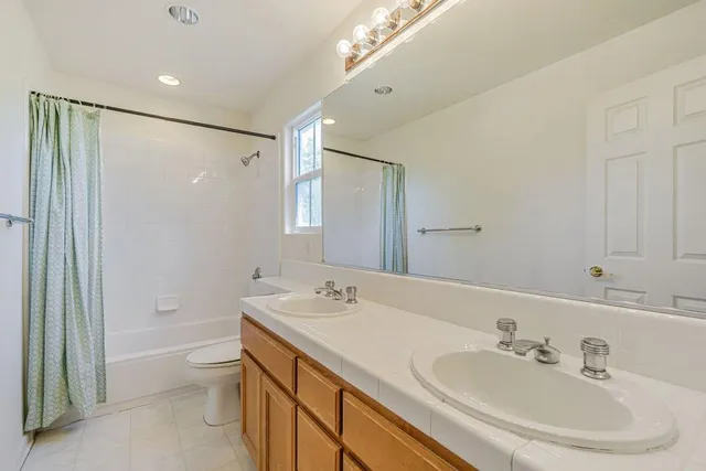 a bathroom with a granite countertop toilet sink and mirror