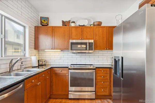 a kitchen with stainless steel appliances granite countertop a sink and a refrigerator