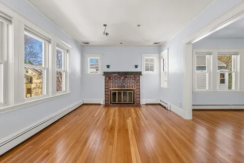 a view of empty room with wooden floor and fireplace