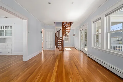 a view of an empty room with wooden floor and a window