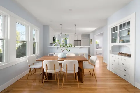 a dining room with furniture a large window and wooden floor