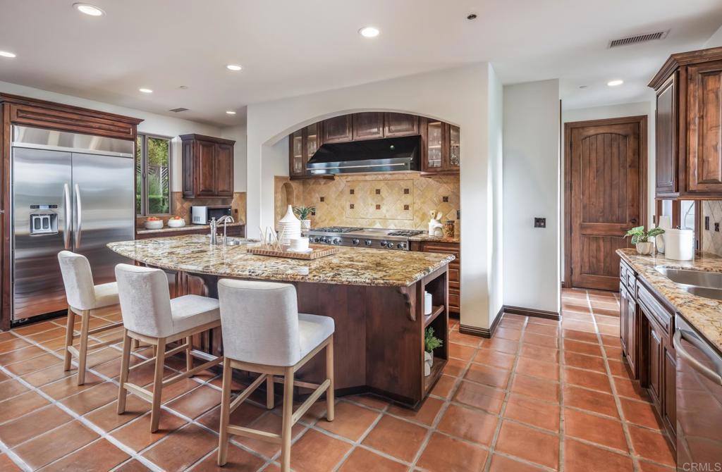 1133 Hermes Avenue Encinitas, CA 92024 - Photo 19 of 40 a kitchen with granite countertop a sink a stove a dining table and chairs