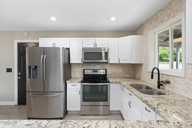 a view of a kitchen with stainless steel appliances refrigerator stove and wooden floor
