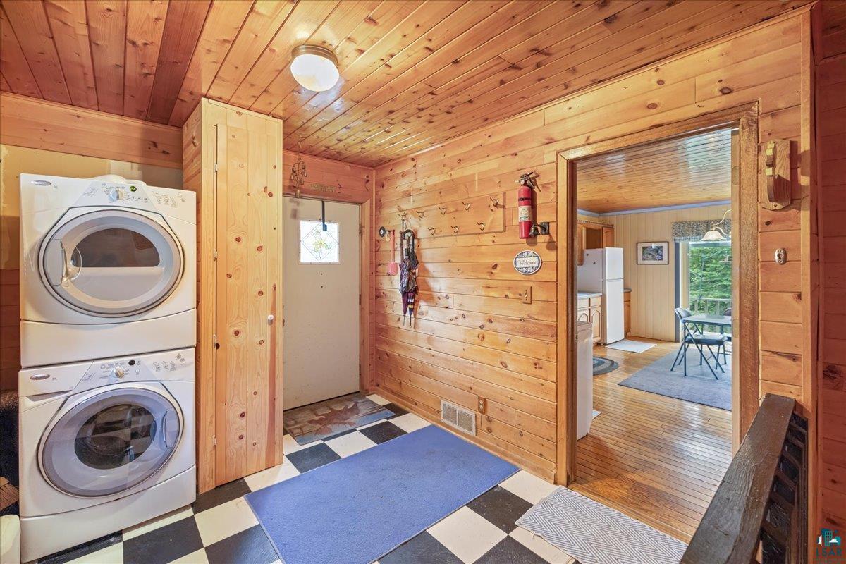 1804 North Bay Road Ely, MN 55731 - Photo 20 of 37 Laundry area featuring wooden walls, wood ceiling, hardwood / wood-style floors, and stacked washing maching and dryer