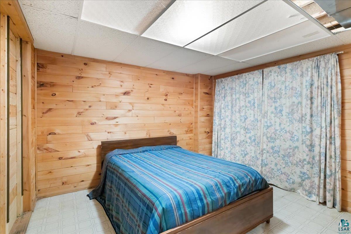 1804 North Bay Road Ely, MN 55731 - Photo 25 of 37 Bedroom featuring tile patterned floors, a drop ceiling, and wooden walls
