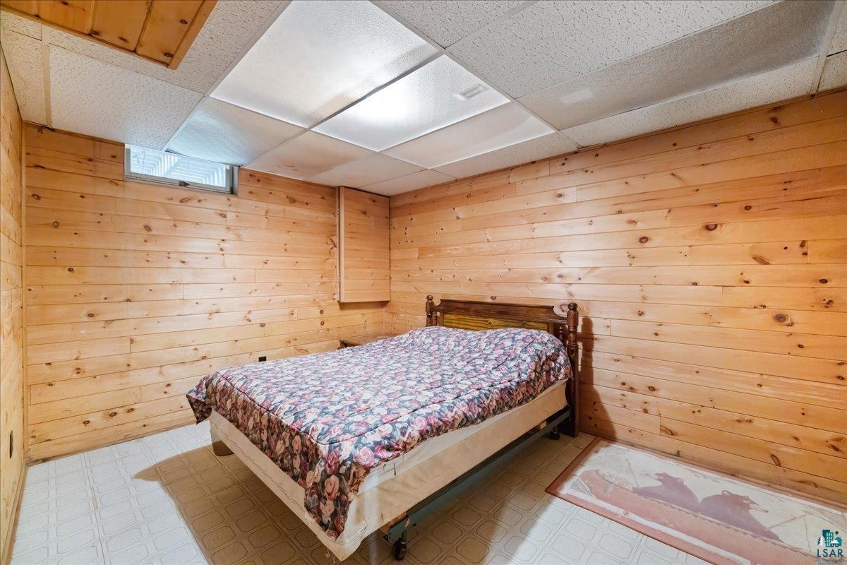 1804 North Bay Road Ely, MN 55731 - Photo 27 of 37 Bedroom with wooden walls, tile patterned flooring, and a paneled ceiling