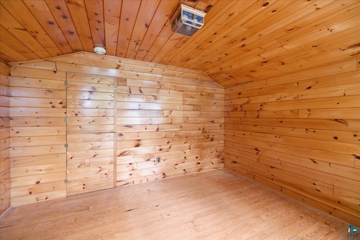 1804 North Bay Road Ely, MN 55731 - Photo 31 of 37 Empty room featuring lofted ceiling, light hardwood / wood-style floors, wood walls, and wooden ceiling
