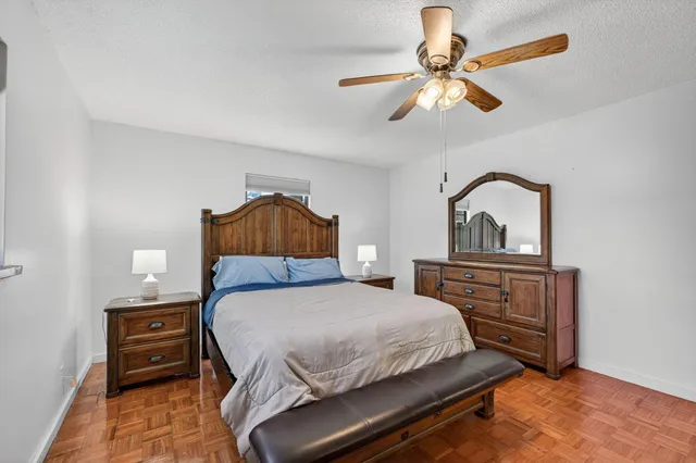 a bedroom with a bed and dresser with wooden floor