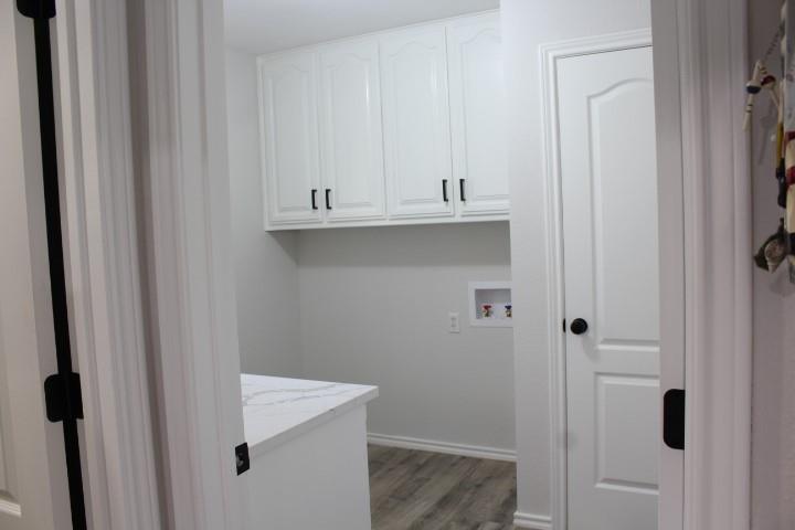 2020 Arbor Bend Road Bonham, TX 75418 - Photo 10 of 19 White shaker-style cabinetry, white quartz-finish countertop, wood-finish flooring, and a panel door with black hardware