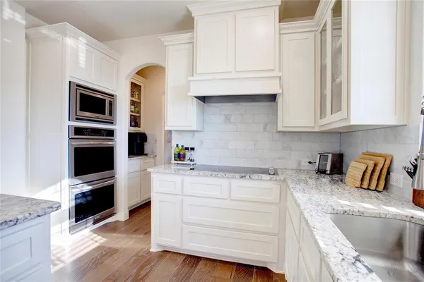 a kitchen with granite countertop a sink a stove and cabinets