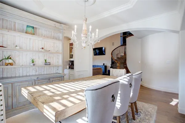 a dining room with wooden floor a chandelier a wooden table and chairs