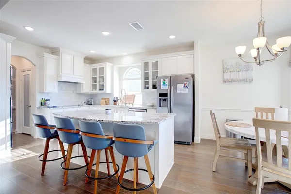 a kitchen with stainless steel appliances kitchen island granite countertop a dining table chairs and a refrigerator