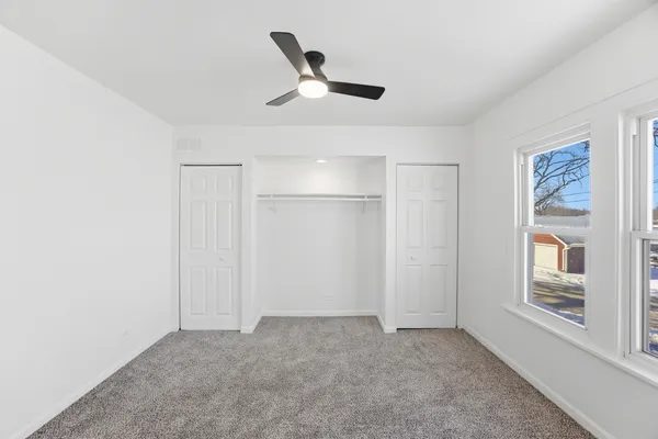 a view of a livingroom with a ceiling fan & windows