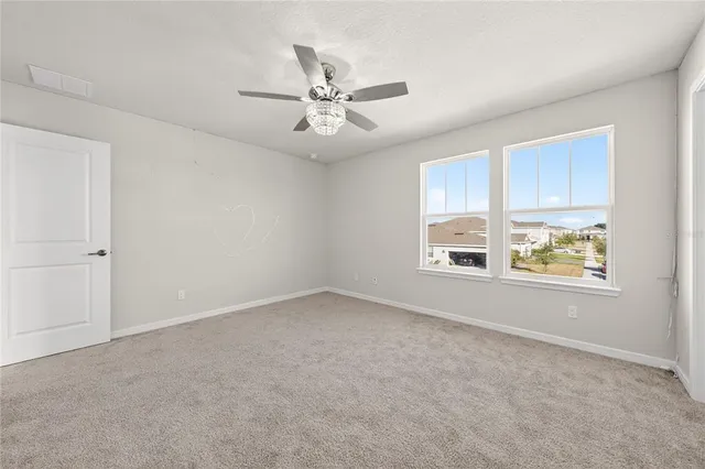 an empty room with fan and windows
