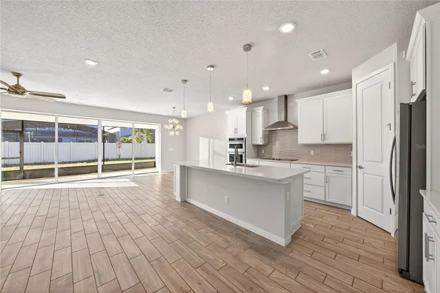 a large white kitchen with a large window and stainless steel appliances