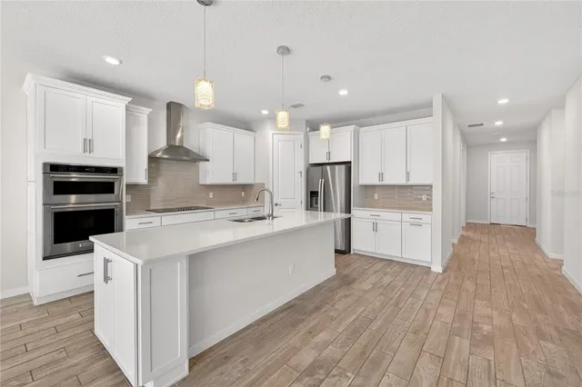 a large kitchen with stainless steel appliances kitchen island a large counter top a stove a refrigerator and a sink