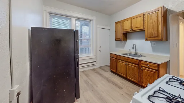 a kitchen with stainless steel appliances granite countertop a refrigerator a sink dishwasher and wooden cabinets with wooden floor