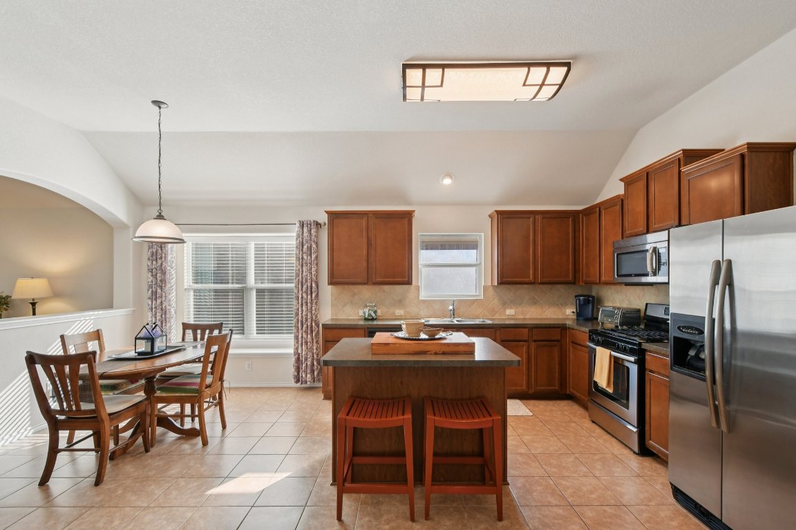 1028 Hot Spring Valley Buda, TX 78610 - Photo 11 of 39 a kitchen with stainless steel appliances a table chairs and a refrigerator