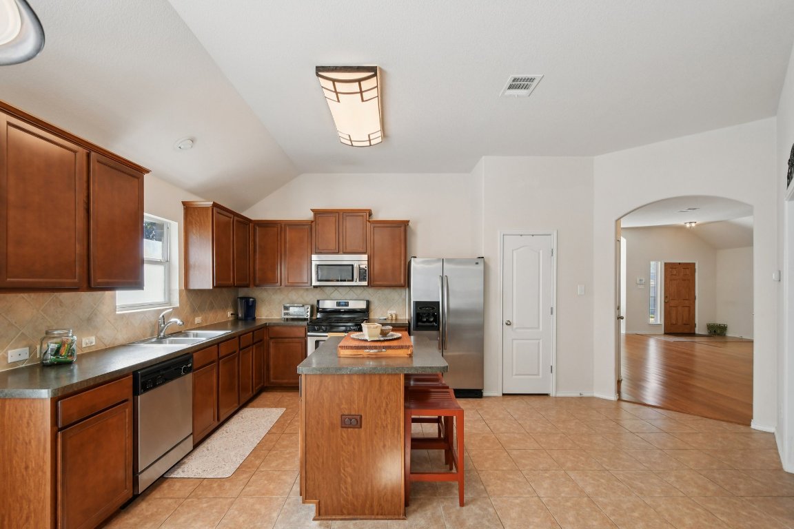 1028 Hot Spring Valley Buda, TX 78610 - Photo 9 of 39 a kitchen with stainless steel appliances granite countertop a stove top oven a sink a refrigerator and cabinets