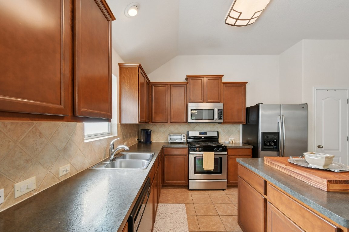 1028 Hot Spring Valley Buda, TX 78610 - Photo 10 of 39 a kitchen with stainless steel appliances a sink stove and refrigerator
