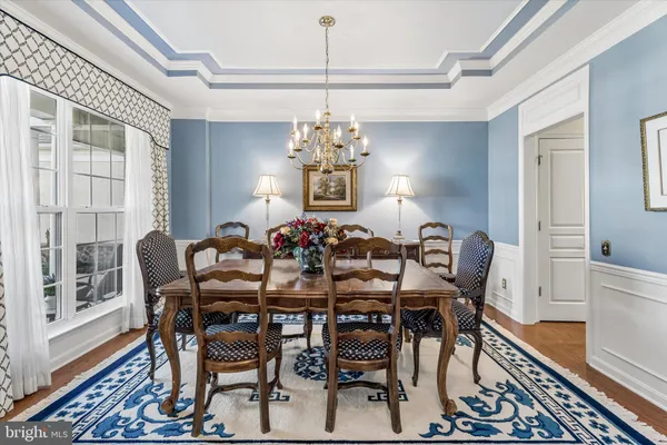 a kitchen with stainless steel appliances a sink a stove a refrigerator cabinets and a dining table with wooden floor