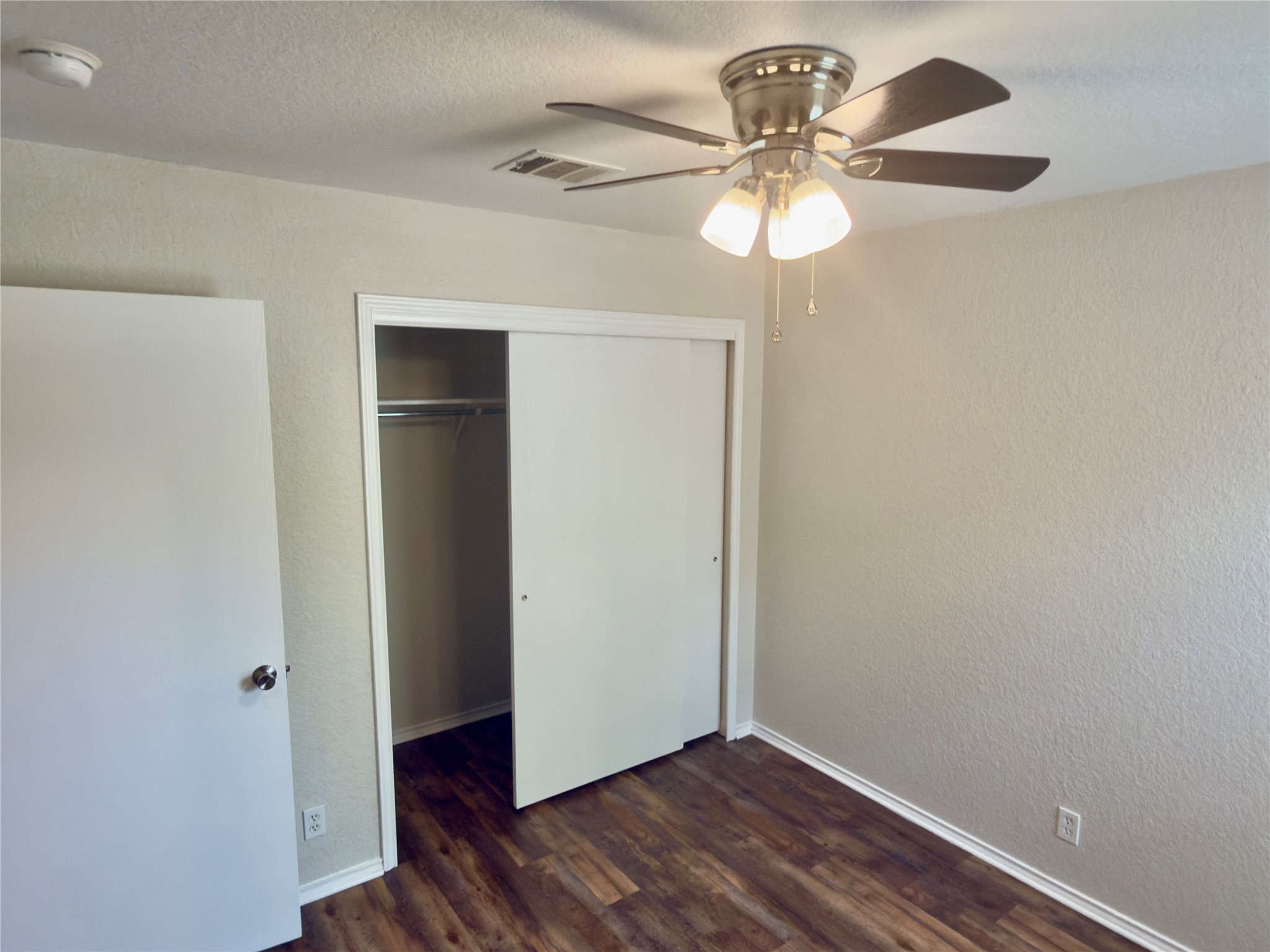 255 Myrtle Street Kyle, TX 78640 - Photo 18 of 31 Bedroom featuring wood-finish flooring, light-colored textured walls, and a ceiling fan with integrated lighting