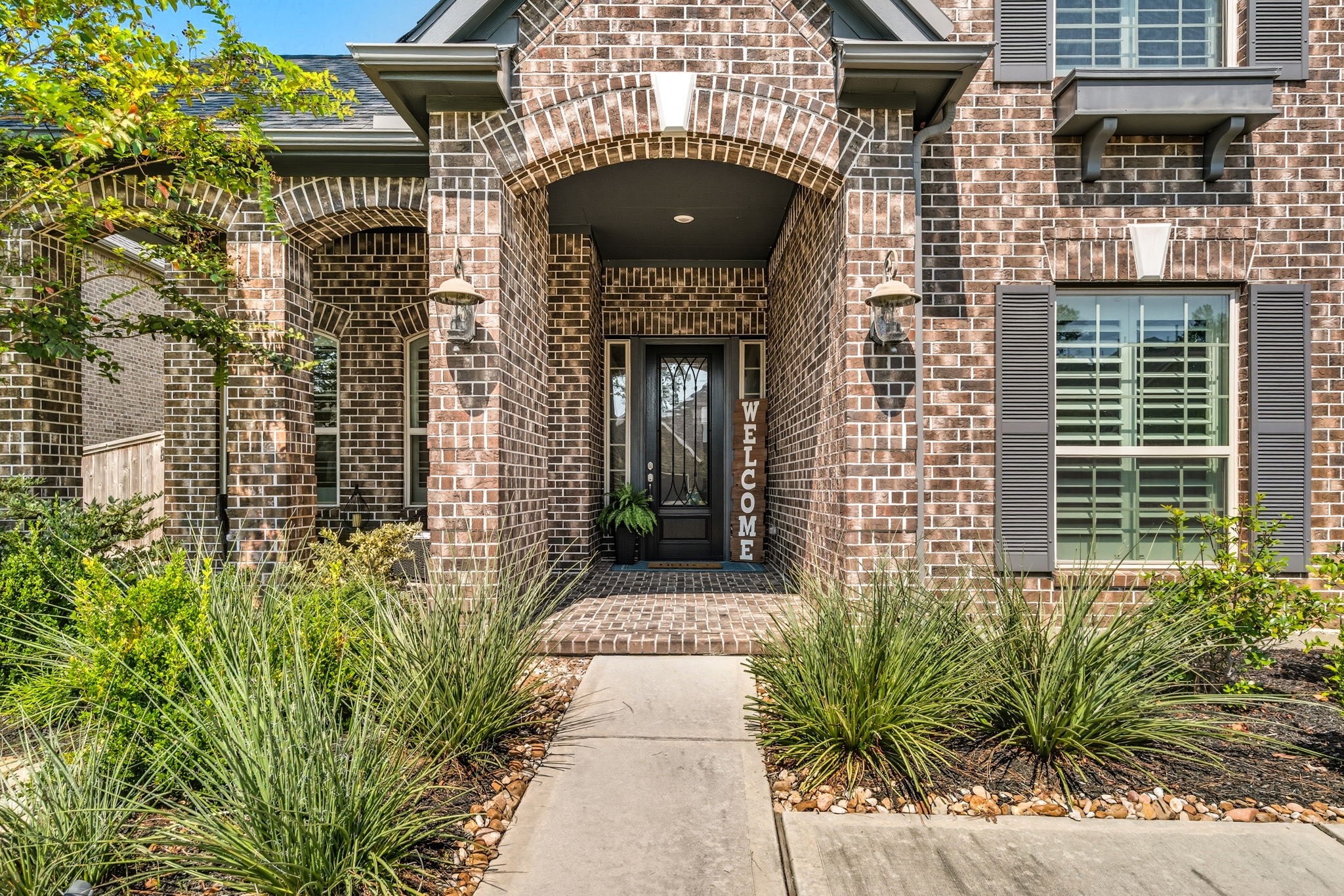 2008 Green Terrace Lane Pinehurst, TX 77362 - Photo 4 of 47 Your new home features a charming brick exterior with an arched entryway, lots of windows accented by elegant shutters and lush landscaping, gorgeous glass panel front door and a large covered front porch.