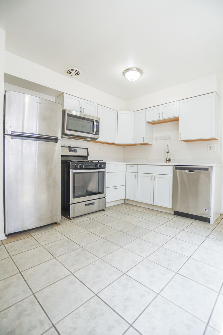 1654 West Pratt Boulevard, Unit 1S Chicago, IL 60626 - Photo 2 of 7 a kitchen with stainless steel appliances granite countertop a refrigerator sink and stove