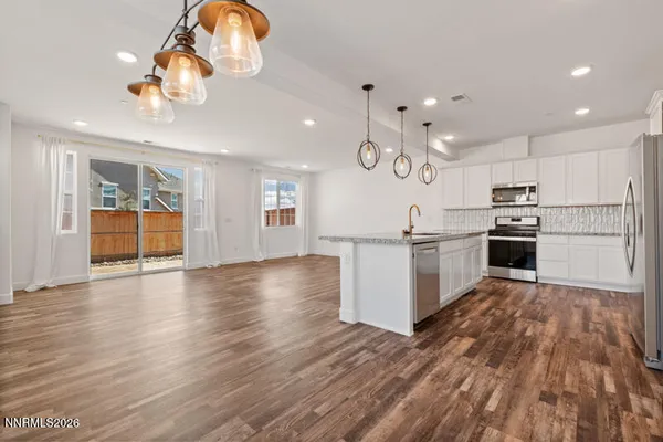 an open kitchen with wooden floor and stainless steel appliances