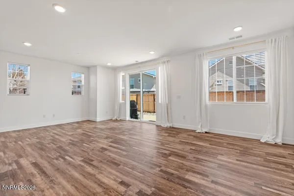 a view of an empty room with wooden floor and windows