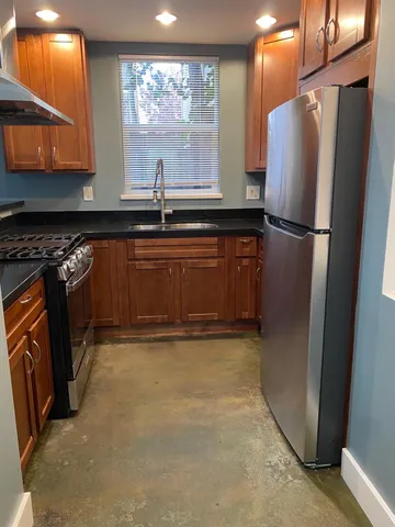 a kitchen with stainless steel appliances granite countertop a refrigerator a stove and a sink