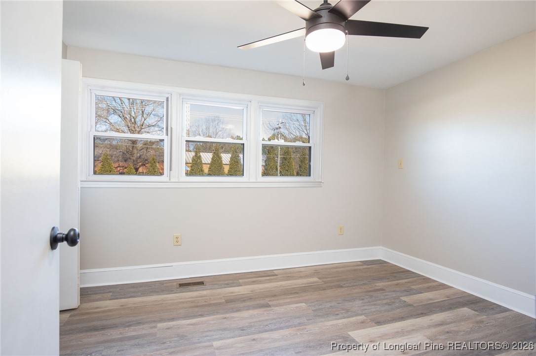 6341 Cliffdale Road Fayetteville, NC 28314 - Photo 14 of 20 an empty room with wooden floor chandelier fan and windows