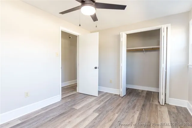 an empty room with wooden floor closet and windows