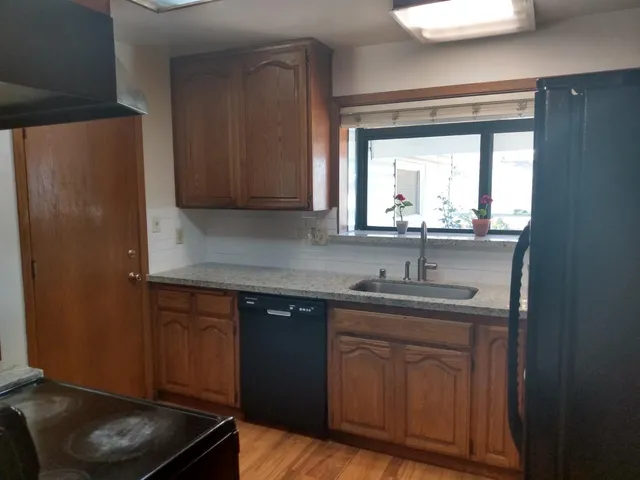 a view of an empty room with wooden floor and a ceiling fan