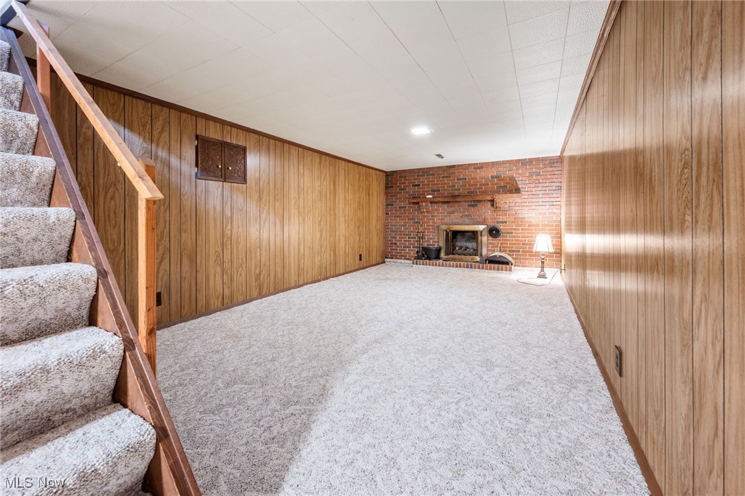 6944 Rolling Ridge Road Northeast Canton, OH 44721 - Photo 18 of 27 Unfurnished basement rec room featuring a brick fireplace, stairs, carpet, and wood walls