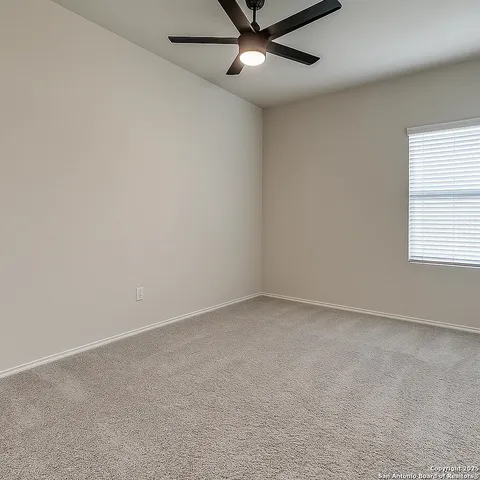 an empty room with a window and a fan