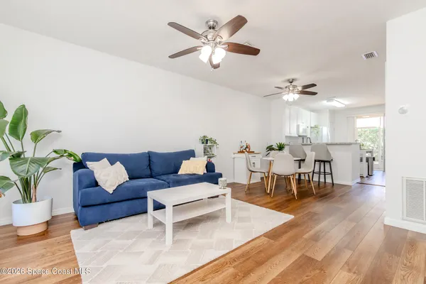 a living room with furniture kitchen view and a chandelier