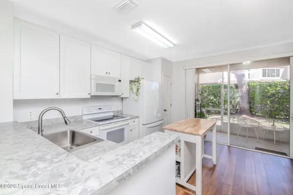 a kitchen with a sink a stove a refrigerator and white cabinets with wooden floor