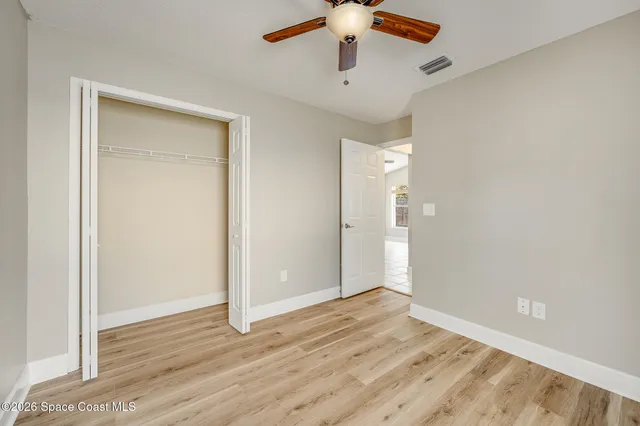an empty room with wooden floor fan and windows