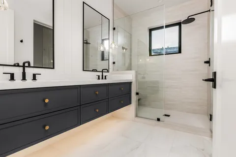 a bathroom with a double vanity sink mirror and shower