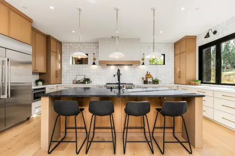 a kitchen with stainless steel appliances granite countertop a sink a stove a refrigerator and island with wooden floor