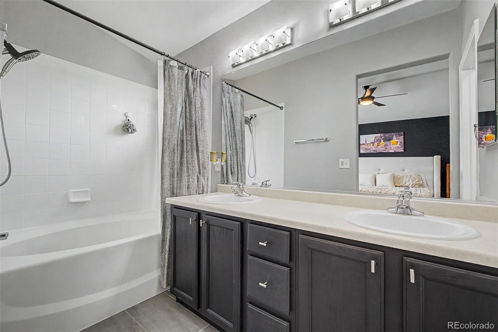 10246 South Spotted Owl Avenue Highlands Ranch, CO 80129 - Photo 31 of 49 a bathroom with a granite countertop sink a mirror a bathtub and shower