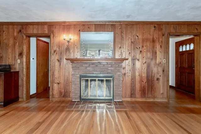 a view of an empty room with wooden floor and a fireplace