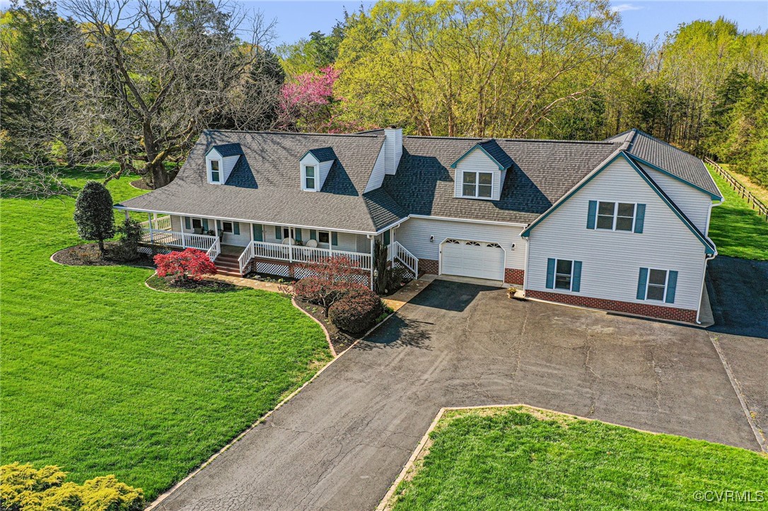 Cape cod home featuring an attached garage, covere
