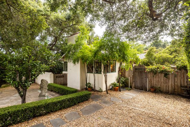a view of a house with large tree and wooden fence